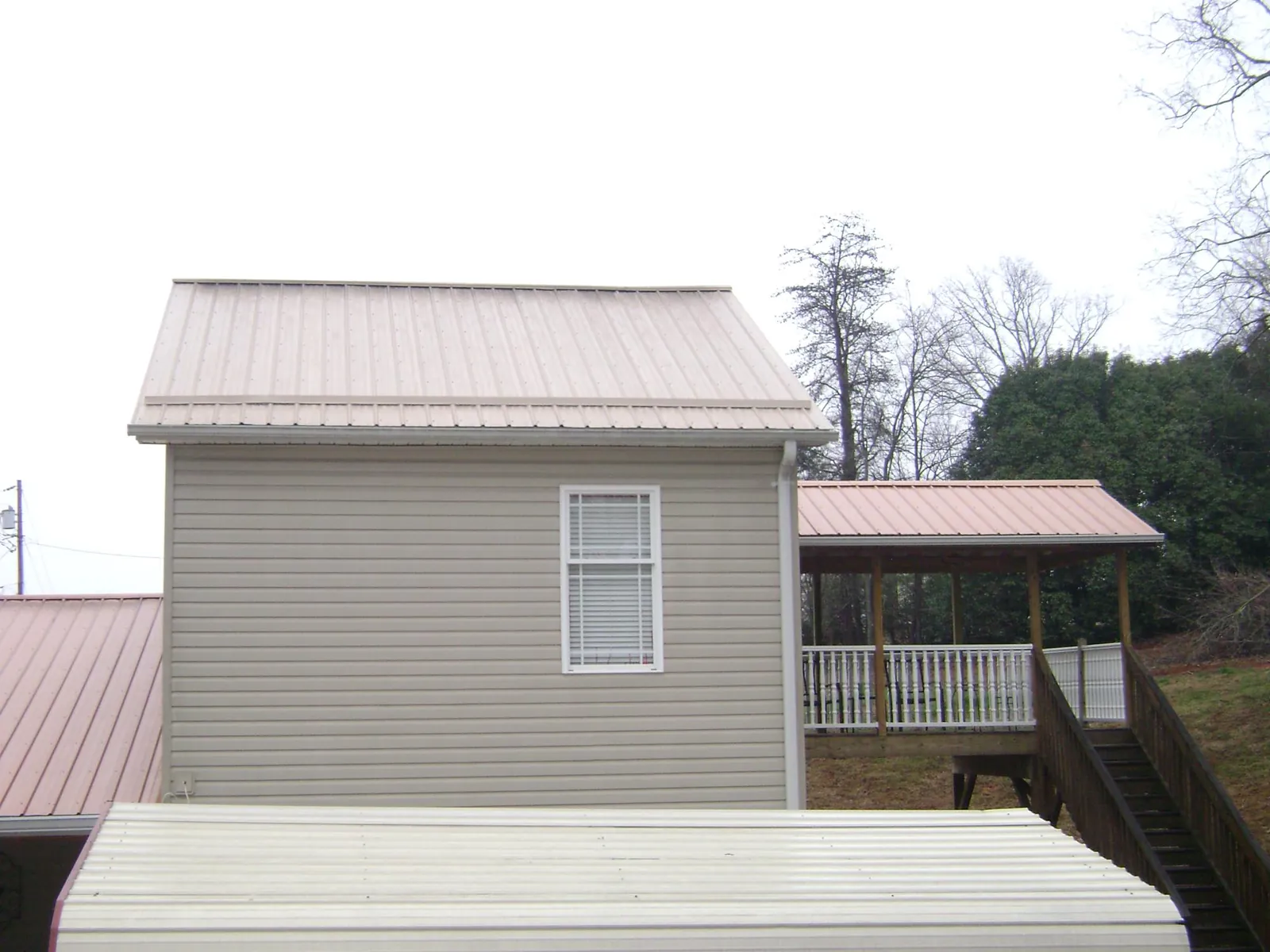 Tan metal roofs on a two story addition and attached porch, from a Roof Replacement job in Princeton